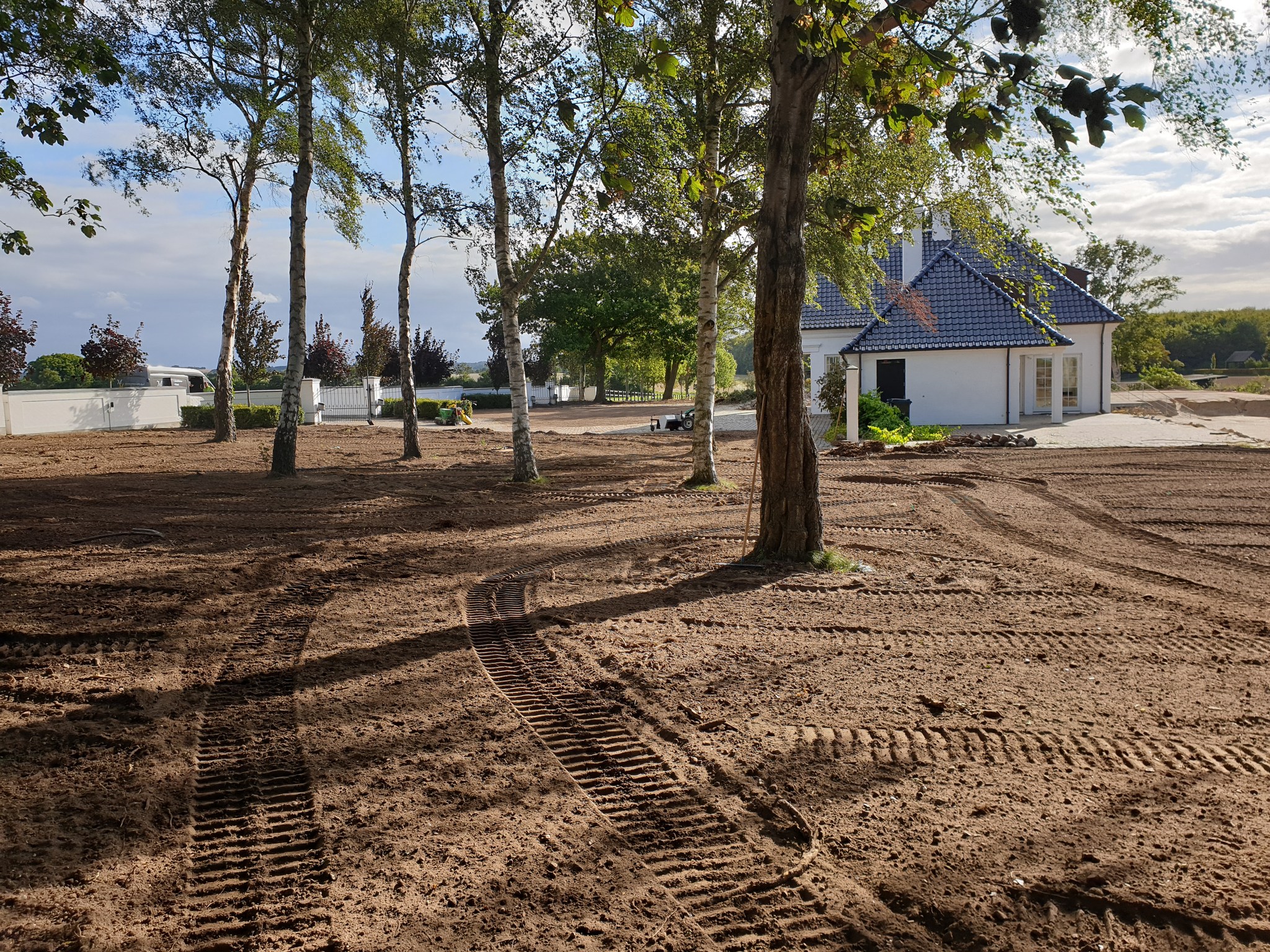 Nygræsset område ved hvid villa på Fyn – klar til spirende plæne og beplantning